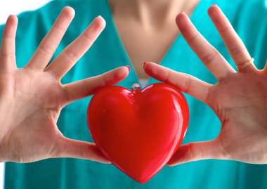 Genç kadın doktor ofisinde kırmızı bir kalp tutan