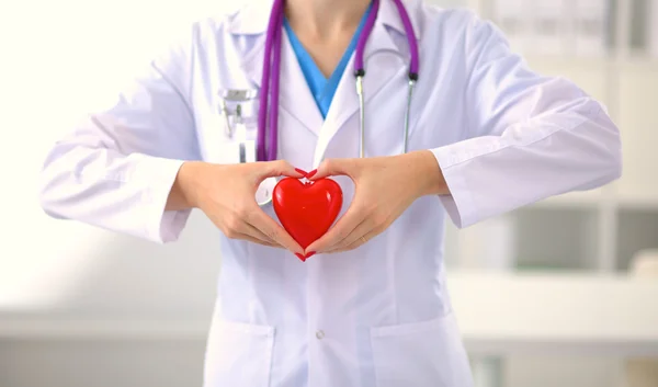 Genç kadın doktor ofisinde kırmızı bir kalp tutan — Stok fotoğraf
