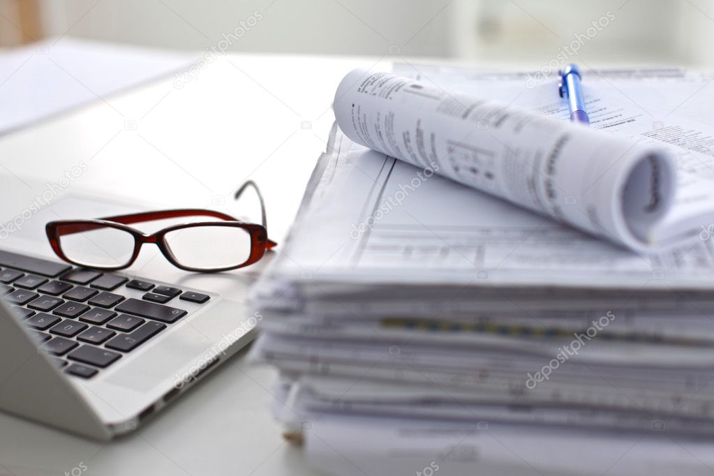 Laptop with stack of folders on table  white background