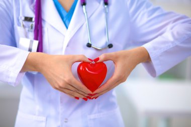Genç kadın doktor ofisinde kırmızı bir kalp tutan