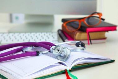 Açık bir kitap bir masanın üzerinde yatan stetoskop
