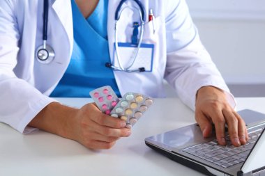 Erkek tıp doktor eller hapları kavanoz tutun ve bir dizüstü bilgisayar klavye üzerinde yazın. Her derde deva hayat kurtar, tedavi, yasal eczane, reçete almak stok, tüketim istatistikleri kavramı
