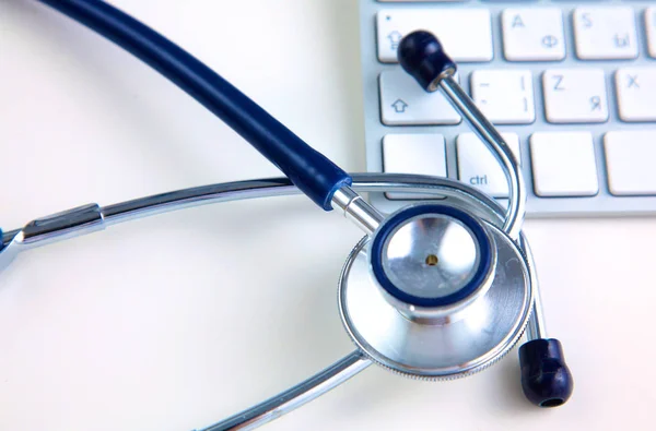 Estetoscopio médico cerca del ordenador portátil en la mesa de madera, blanco — Foto de Stock