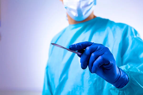 Homem cirurgião segura um bisturi em uma sala de cirurgia — Fotografia de Stock