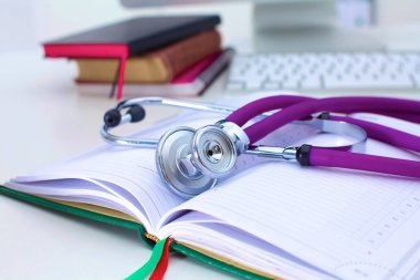 Açık bir kitap bir masanın üzerinde yatan stetoskop