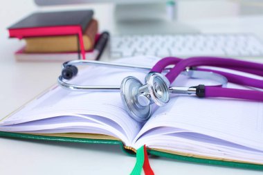 Açık bir kitap bir masanın üzerinde yatan stetoskop