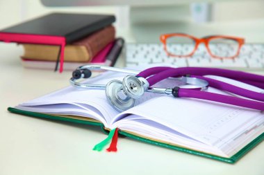 Açık bir kitap bir masanın üzerinde yatan stetoskop