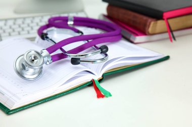 Açık bir kitap bir masanın üzerinde yatan stetoskop