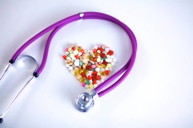 Stetoskop ve beyaz arka planda izole edilmiş bazı haplar.