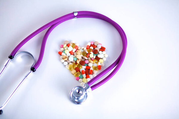 Стетоскоп и некоторые таблетки - изолированы на белом фоне
