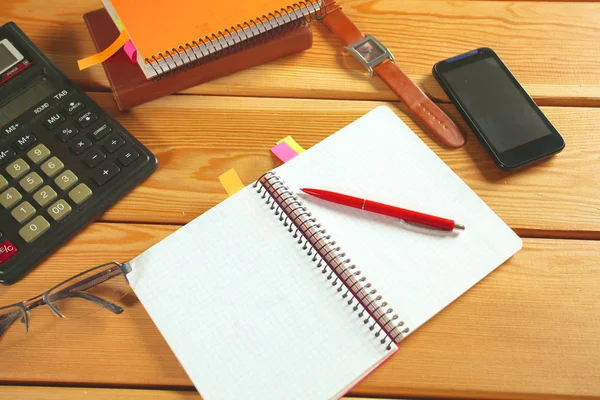 Surface of a wooden table with notebook, smartphone, eye glasses, and pen — Stock Photo, Image