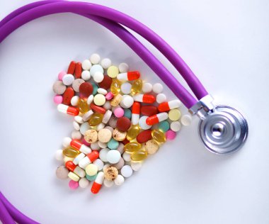 Stetoskop ve beyaz arka planda izole edilmiş bazı haplar.