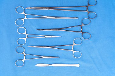 Ameliyat için masaya yerleştirilmiş neşter, pens ve cımbız gibi cerrahi aletler ve aletler.