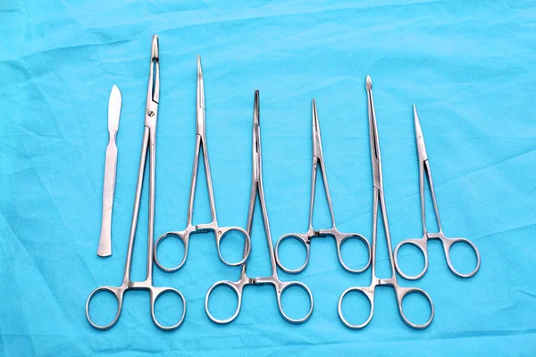 Instruments et outils chirurgicaux, y compris scalpels, pinces et pinces à épiler, disposés sur une table pour une intervention chirurgicale — Photo