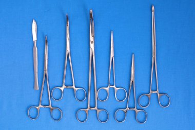 Ameliyat için masaya yerleştirilmiş neşter, pens ve cımbız gibi cerrahi aletler ve aletler.