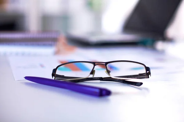 Glasses and pen in focus lie on the table Royalty Free Stock Photos
