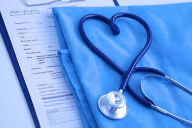 Sağlık stetoskop yalan hasta tıbbi geçmiş listesi ve mavi doktor Tekdüzen portre üzerinde kalp şeklinde bükülmüş. Tıbbi yardım veya sigorta kavramı. Kardiyoloji Bakımı, sağlık, koruma ve korunma