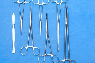 Ameliyat için masaya yerleştirilmiş neşter, pens ve cımbız gibi cerrahi aletler ve aletler.