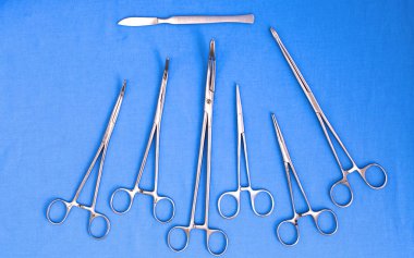 Ameliyat için masaya yerleştirilmiş neşter, pens ve cımbız gibi cerrahi aletler ve aletler.