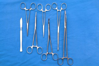 Ameliyat için masaya yerleştirilmiş neşter, pens ve cımbız gibi cerrahi aletler ve aletler.