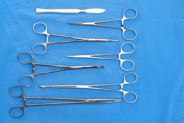 Ameliyat için masaya yerleştirilmiş neşter, pens ve cımbız gibi cerrahi aletler ve aletler.