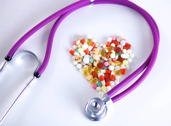 Großaufnahme von Tabletten auf dem Tisch mit Stethoskop und daneben liegendem Herz — Stockfoto