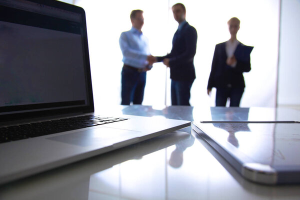 Рабочий стол и планшет на фоне бизнес-команды
