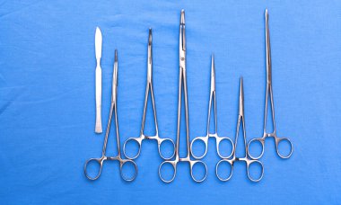 Ameliyat için masaya yerleştirilmiş neşter, pens ve cımbız gibi cerrahi aletler ve aletler.