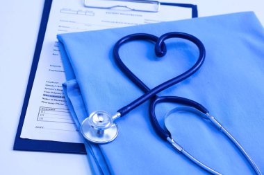 Sağlık stetoskop yalan hasta tıbbi geçmiş listesi ve mavi doktor Tekdüzen portre üzerinde kalp şeklinde bükülmüş