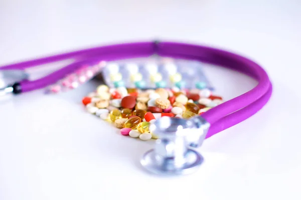 Close up of pills spread over the table with stethoscope and heart lying beside — Stock Photo, Image