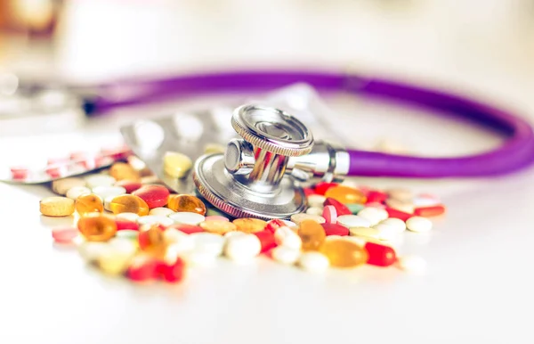 Zblízka pilulek rozloženo v tabulce s stetoskop a srdcem ležící vedle — Stock fotografie