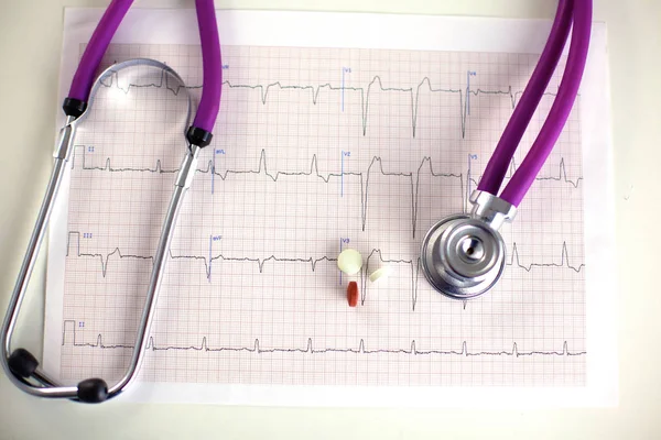 Zblízka pilulek rozloženo v tabulce s stetoskop a srdcem ležící vedle — Stock fotografie