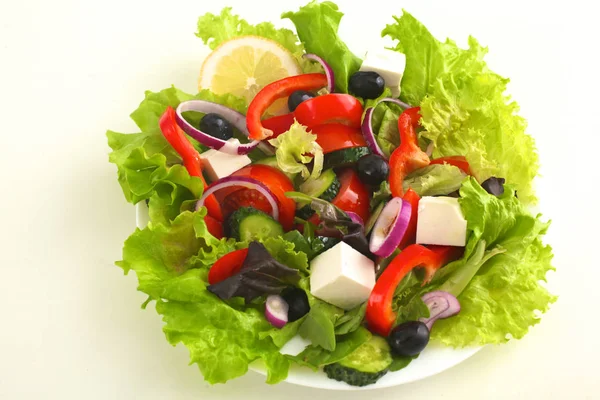 Sallad på färska grönsaker och örter på bordet i plattan — Stockfoto