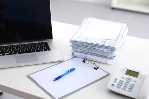 Laptop with stack of folders on table on white background