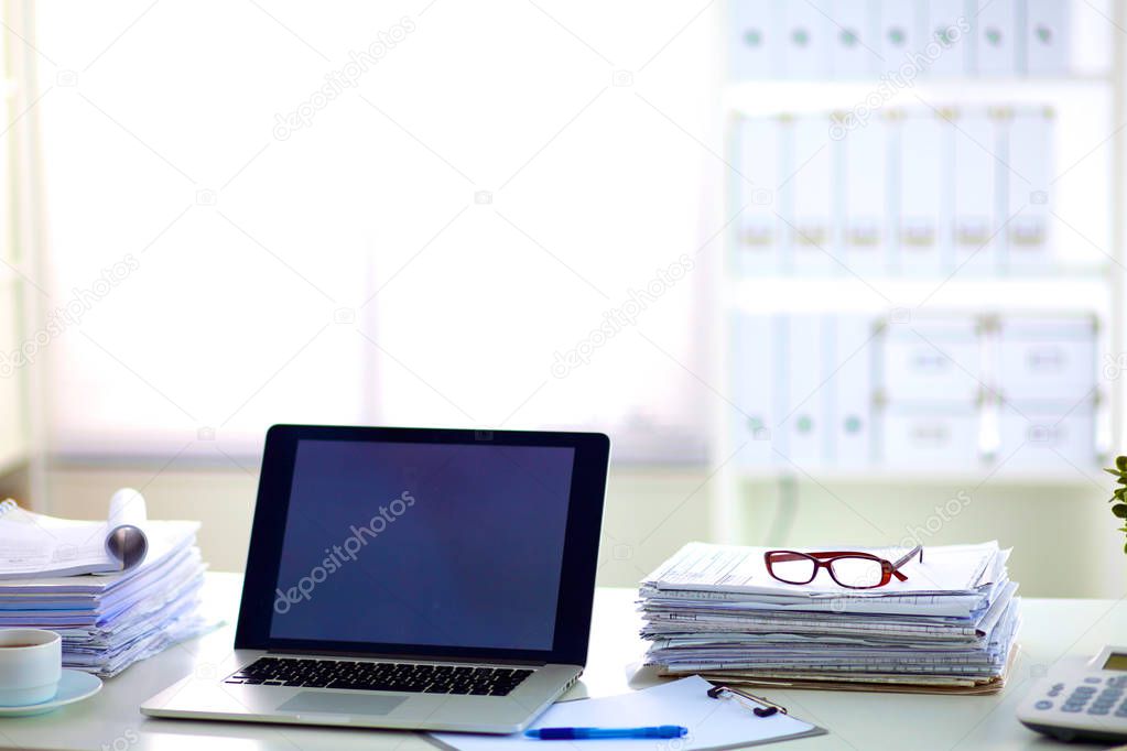 Laptop with stack of folders on table on white background