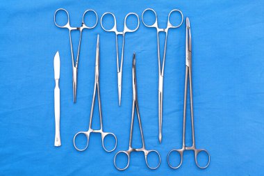 Ameliyat için masaya yerleştirilmiş neşter, pens ve cımbız gibi cerrahi aletler ve aletler.