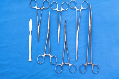 Ameliyat için masaya yerleştirilmiş neşter, pens ve cımbız gibi cerrahi aletler ve aletler.