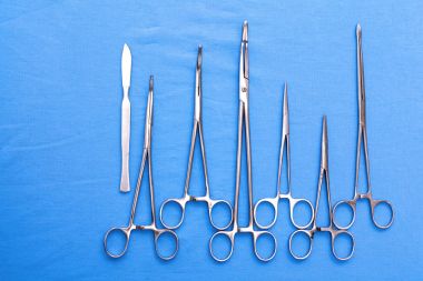 Ameliyat için masaya yerleştirilmiş neşter, pens ve cımbız gibi cerrahi aletler ve aletler.