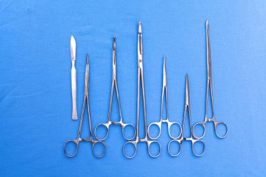 Ameliyat için masaya yerleştirilmiş neşter, pens ve cımbız gibi cerrahi aletler ve aletler.