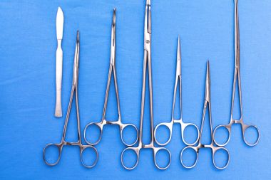 Ameliyat için masaya yerleştirilmiş neşter, pens ve cımbız gibi cerrahi aletler ve aletler.