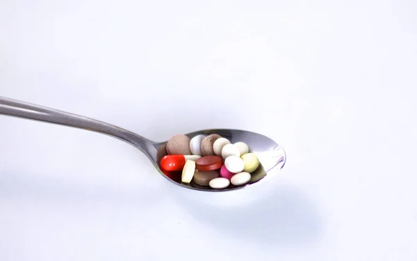 Viele bunte Pillen auf einem Löffel. Foto-Ikone gegen Tablettensucht — Stockfoto