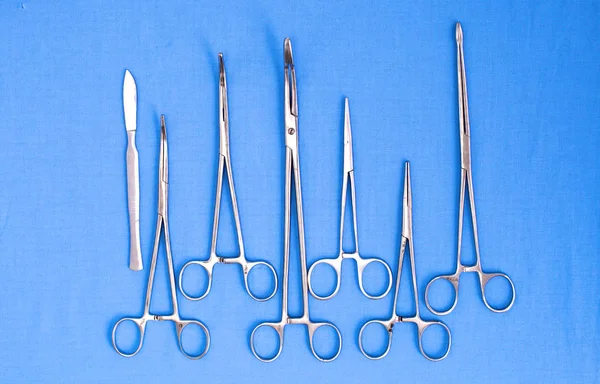Ameliyat için masaya yerleştirilmiş neşter, pens ve cımbız gibi cerrahi aletler ve aletler.