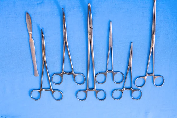 Ameliyat için masaya yerleştirilmiş neşter, pens ve cımbız gibi cerrahi aletler ve aletler. — Stok fotoğraf