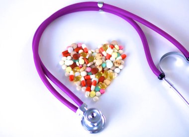 Stetoskop ve beyaz arka planda izole edilmiş bazı haplar.