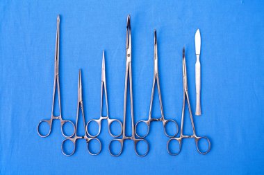 Ameliyat için masaya yerleştirilmiş neşter, pens ve cımbız gibi cerrahi aletler ve aletler.