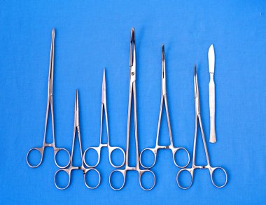 Ameliyat için masaya yerleştirilmiş neşter, pens ve cımbız gibi cerrahi aletler ve aletler.