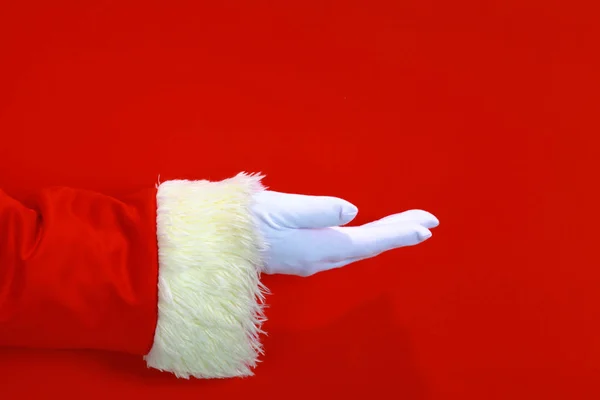 Papai Noel mão apresentando seu texto de Natal ou produto sobre fundo vermelho com espaço de cópia — Fotografia de Stock