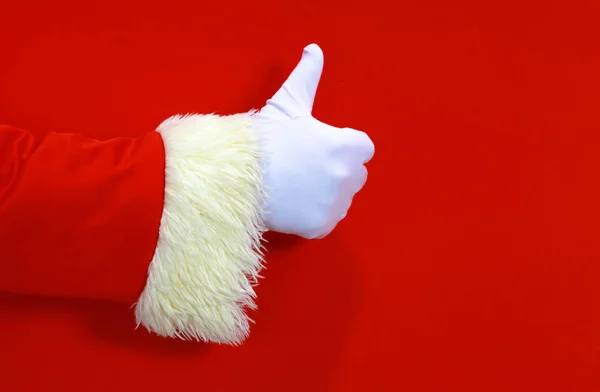 Santa Claus hand presenting your christmas text or product over red background with copy space — Stock Photo, Image