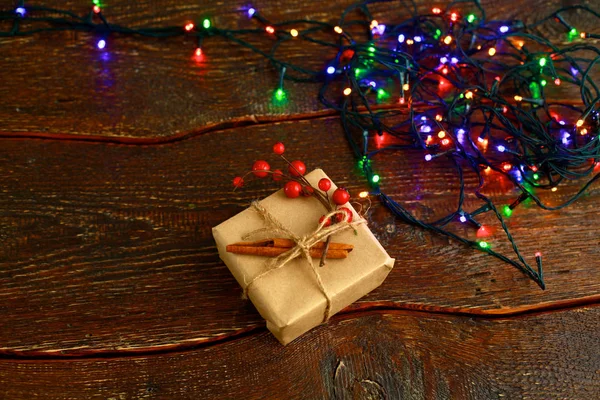 Новорічний подарунок або подарункова коробка, загорнута в крафт-папір з прикрасою на сільському дерев'яному фоні — стокове фото