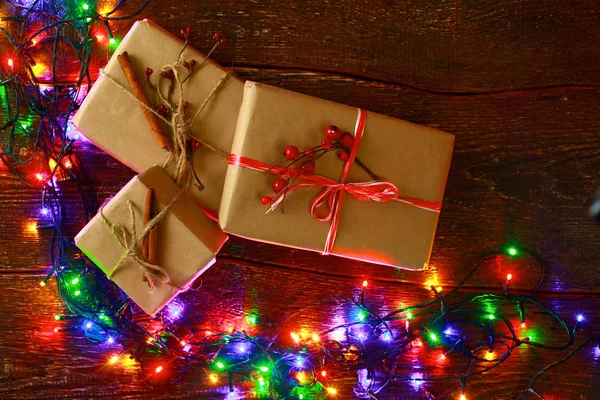 Новорічний подарунок або подарункова коробка, загорнута в крафт-папір з прикрасою на сільському дерев'яному фоні — стокове фото